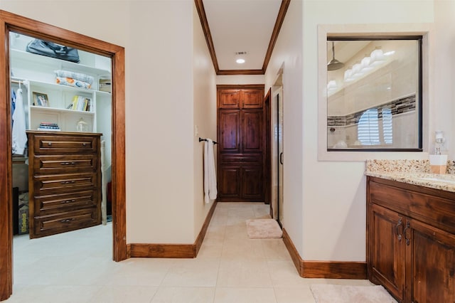 hallway with baseboards, ornamental molding, and light tile patterned floors