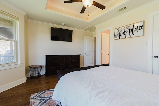 bedroom with ornamental molding, wood finished floors, a raised ceiling, and visible vents