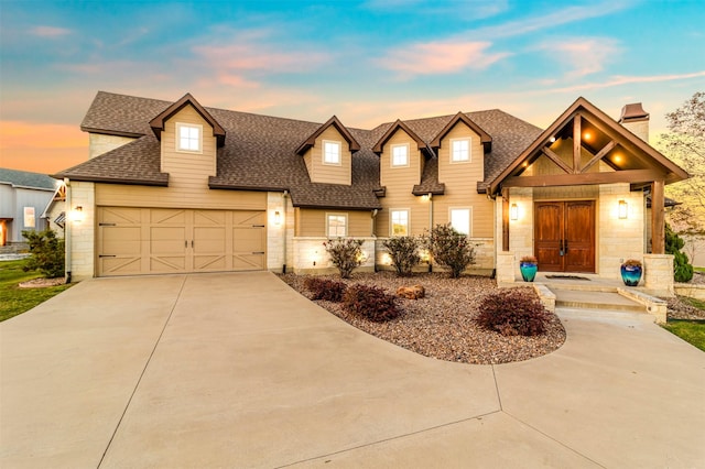 view of front facade with a garage, stone siding, a chimney, a shingled roof, and driveway