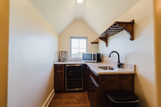 bar with wine cooler, dark wood finished floors, stainless steel microwave, vaulted ceiling, and a sink