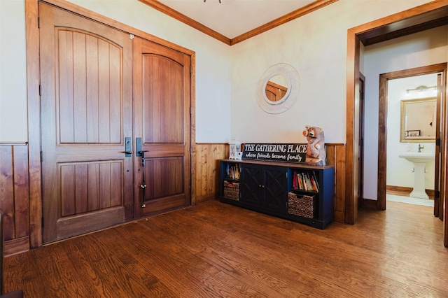 foyer entrance with wooden walls, dark wood-style flooring, ornamental molding, and a wainscoted wall