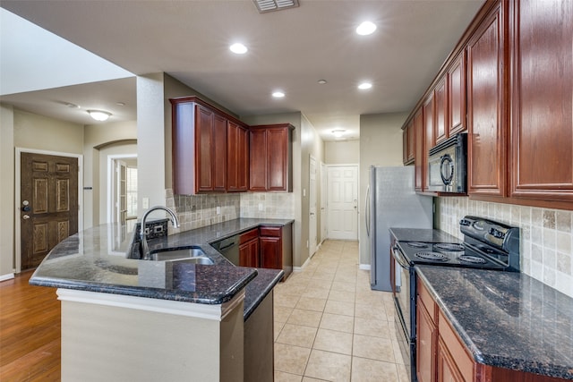 kitchen featuring backsplash, dark stone counters, black appliances, sink, and kitchen peninsula