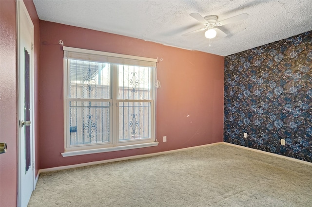 empty room featuring ceiling fan, light colored carpet, and a textured ceiling