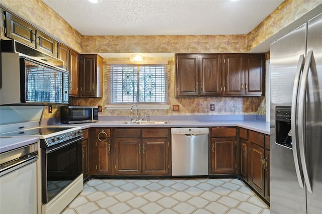 kitchen with dark brown cabinets, sink, stainless steel appliances, and a textured ceiling