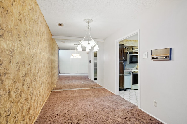 hall with a chandelier, light colored carpet, and a textured ceiling