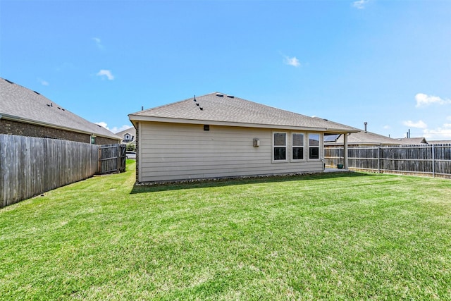 rear view of property with a yard, a fenced backyard, and a shingled roof