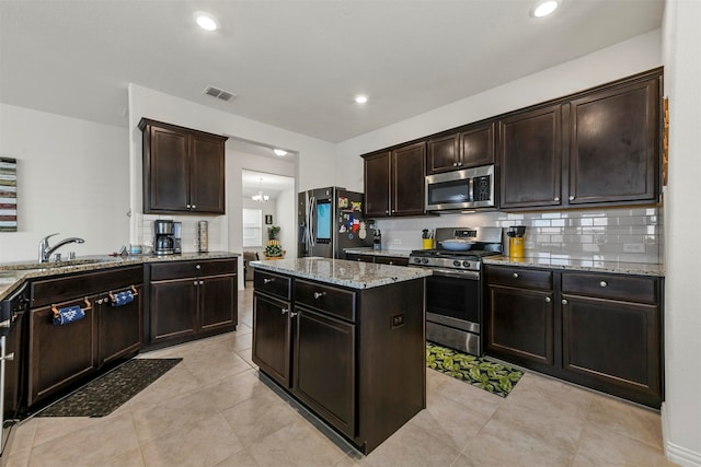 kitchen featuring appliances with stainless steel finishes, dark brown cabinets, sink, a chandelier, and a center island