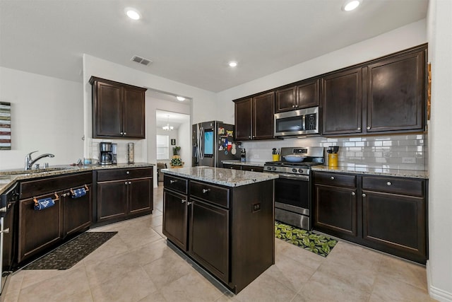 kitchen with light stone countertops, visible vents, a sink, decorative backsplash, and stainless steel appliances