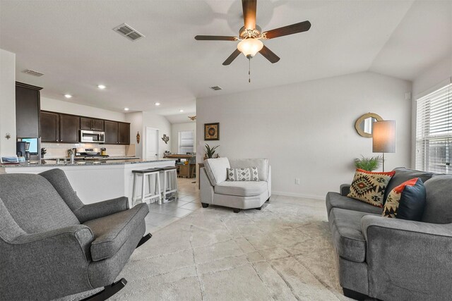 living room with ceiling fan, lofted ceiling, and light tile patterned flooring