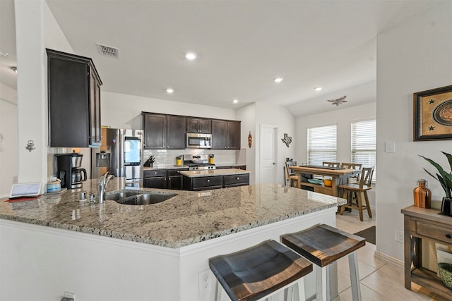 kitchen featuring sink, light stone countertops, appliances with stainless steel finishes, tasteful backsplash, and kitchen peninsula