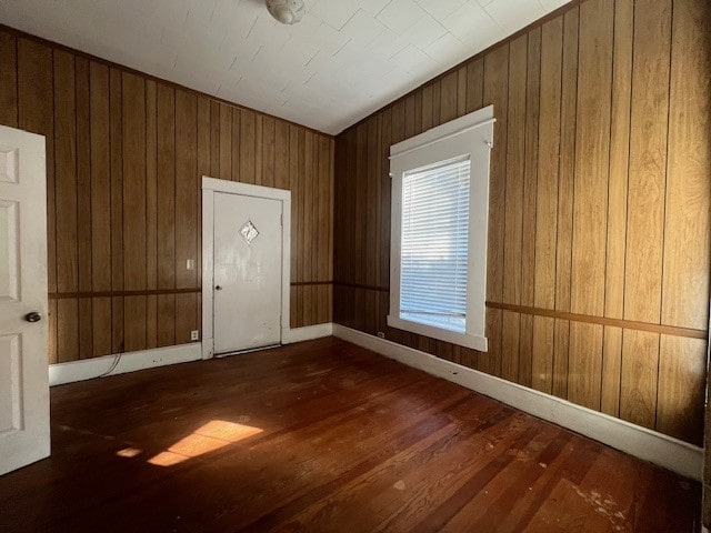 entrance foyer featuring dark hardwood / wood-style flooring and wooden walls