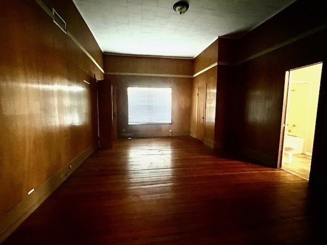 empty room featuring dark hardwood / wood-style floors and wooden walls