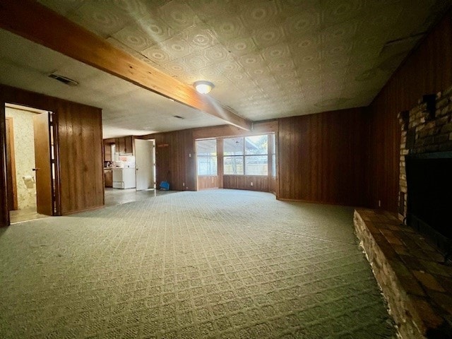 unfurnished living room with carpet flooring, a fireplace, and wooden walls