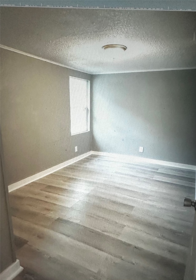 empty room with hardwood / wood-style flooring and a textured ceiling