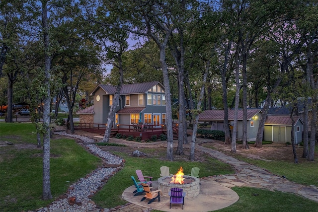 rear view of house featuring metal roof, a fire pit, a deck, and a lawn