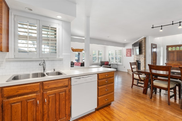 kitchen featuring sink, a brick fireplace, light hardwood / wood-style flooring, track lighting, and white dishwasher