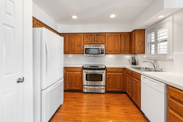 kitchen with sink, backsplash, light wood-type flooring, and appliances with stainless steel finishes