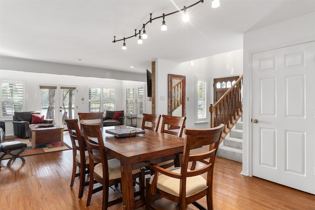 dining space with rail lighting, french doors, and light wood-type flooring