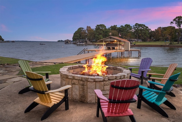 patio terrace at dusk featuring a dock, a water view, and a fire pit