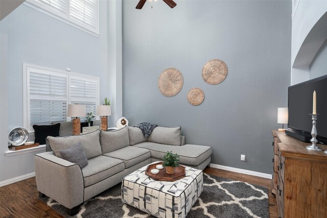 living room with a towering ceiling, dark hardwood / wood-style floors, and ceiling fan