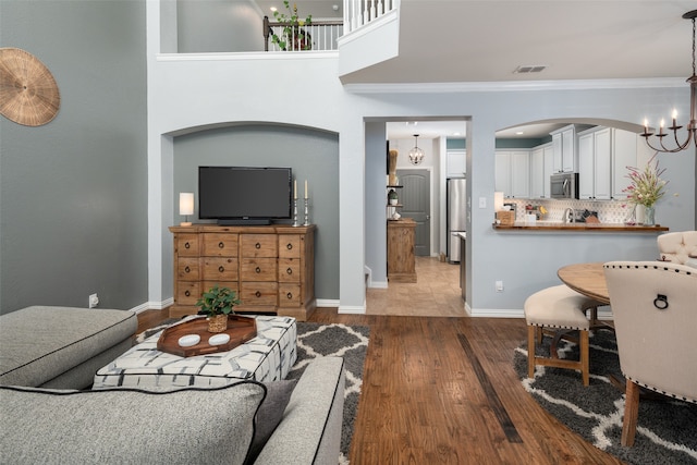 living room featuring ornamental molding, wood-type flooring, and a notable chandelier