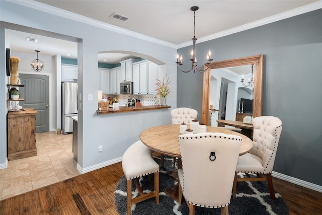 dining room with light hardwood / wood-style flooring, ornamental molding, and a notable chandelier