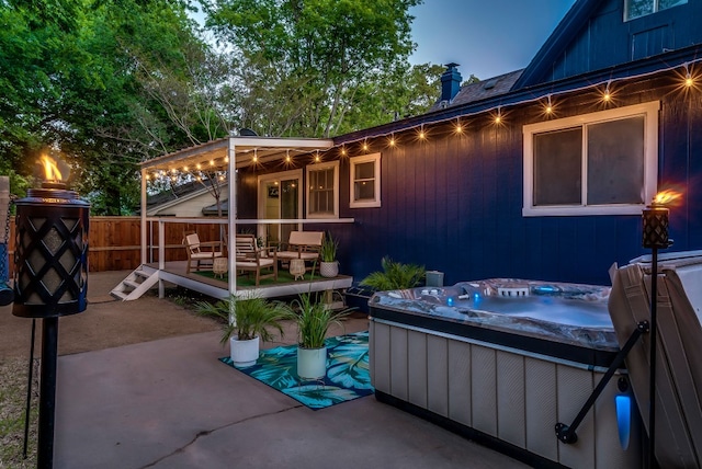 patio terrace at dusk featuring a hot tub and a deck