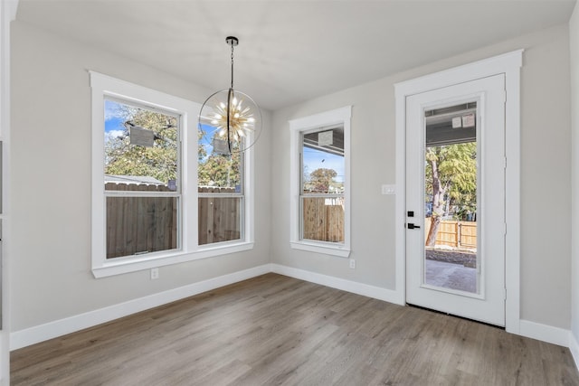 unfurnished dining area with light hardwood / wood-style flooring and a notable chandelier