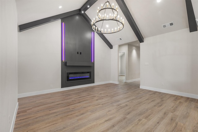 unfurnished living room with a fireplace, lofted ceiling with beams, a notable chandelier, and light hardwood / wood-style floors