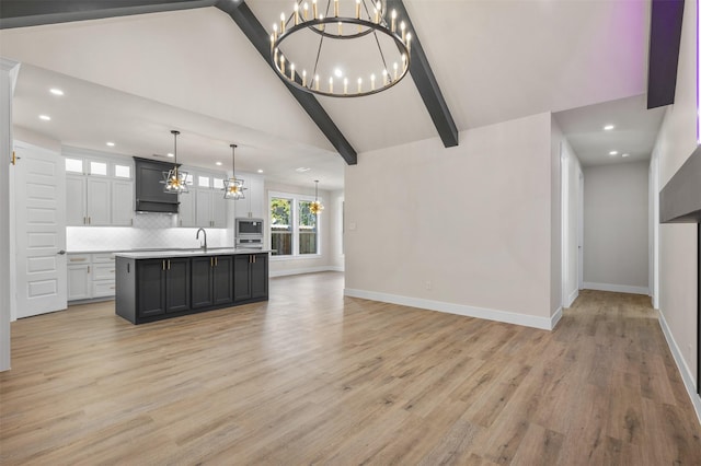 kitchen featuring backsplash, a center island with sink, light hardwood / wood-style flooring, and hanging light fixtures