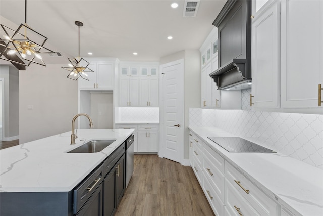 kitchen featuring black electric stovetop, white cabinetry, sink, and hanging light fixtures