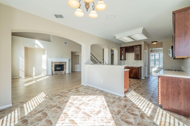 kitchen featuring an inviting chandelier, tile patterned flooring, a tiled fireplace, and black electric cooktop