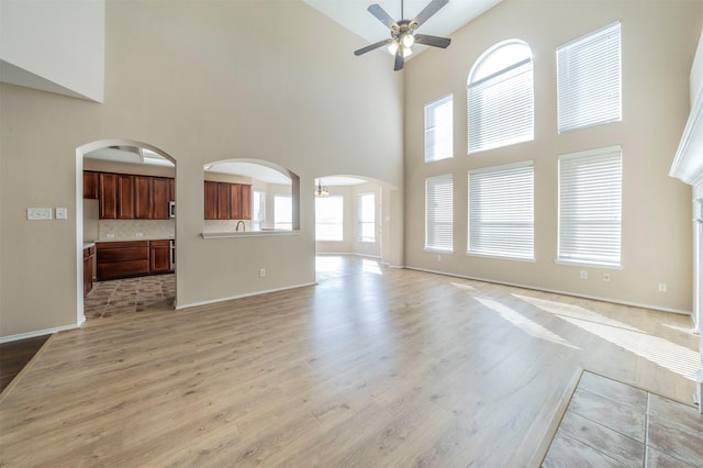 unfurnished living room featuring light hardwood / wood-style flooring, a towering ceiling, and a healthy amount of sunlight