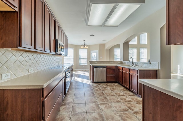 kitchen with sink, tasteful backsplash, decorative light fixtures, light tile patterned floors, and stainless steel appliances