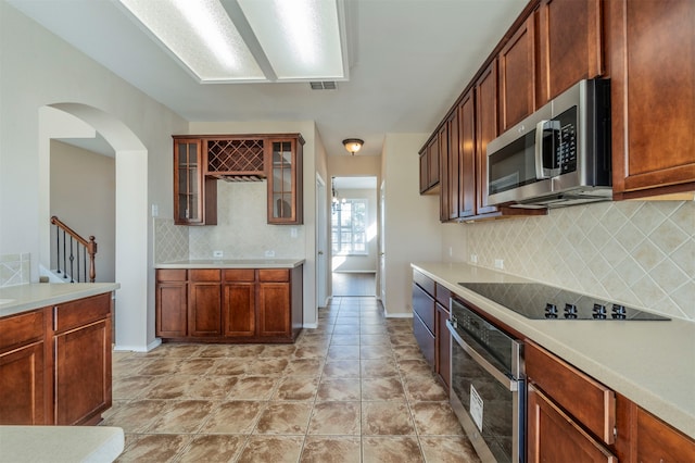 kitchen with backsplash, light tile patterned floors, and appliances with stainless steel finishes