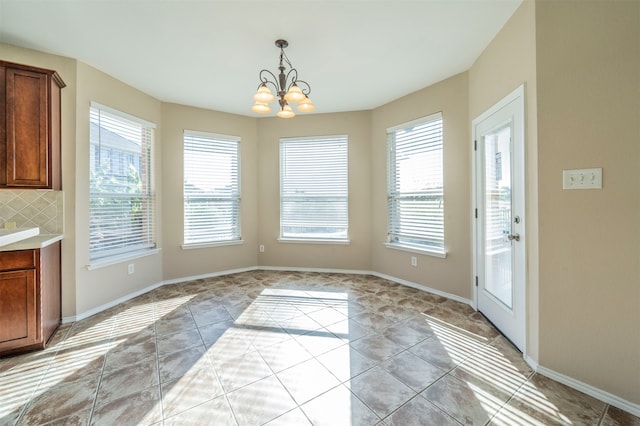 unfurnished dining area with light tile patterned floors, an inviting chandelier, and a wealth of natural light