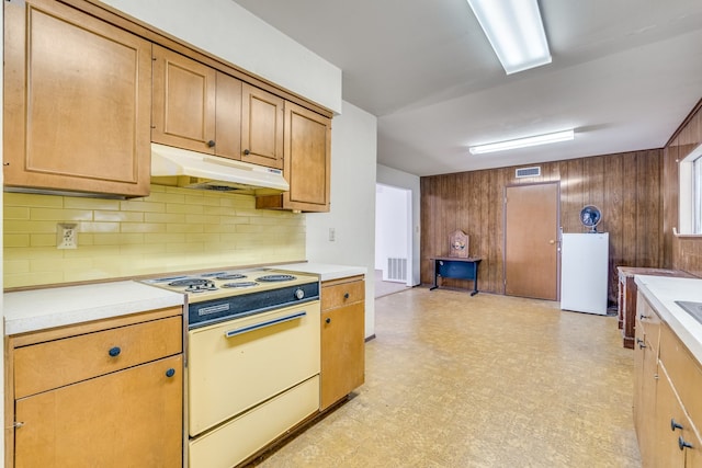 kitchen with decorative backsplash, wood walls, and white appliances