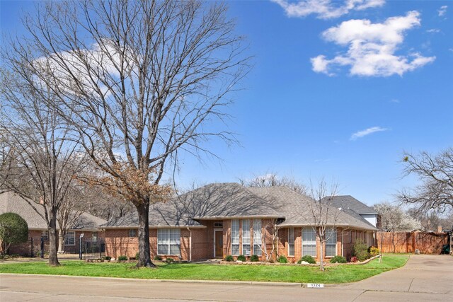 view of front of house featuring brick siding, a front yard, and fence