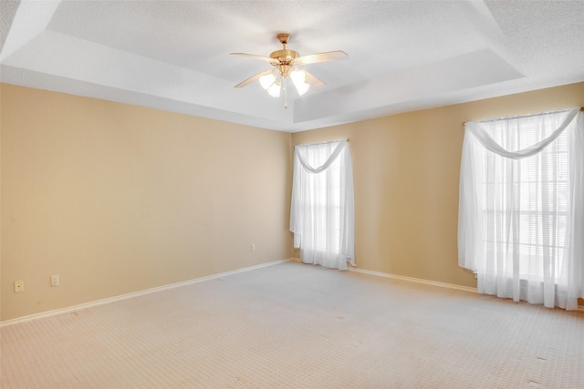 unfurnished room with light carpet, a tray ceiling, and plenty of natural light