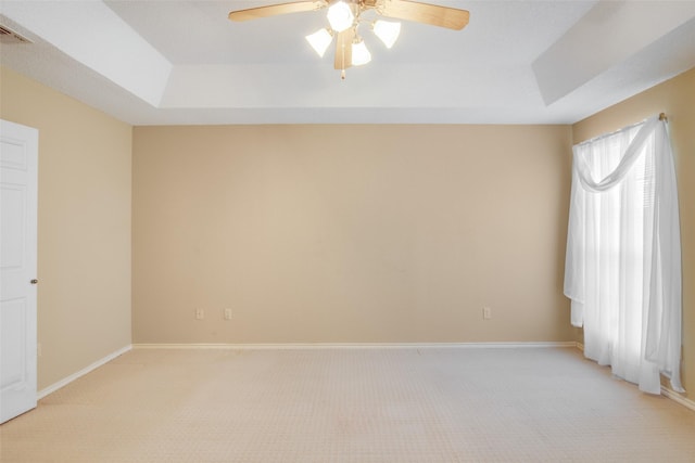 carpeted empty room featuring a raised ceiling and ceiling fan