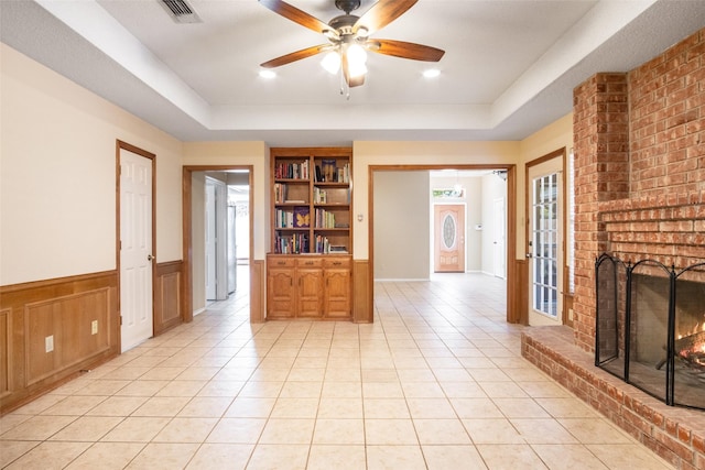 interior space featuring a tray ceiling, light tile patterned floors, and a brick fireplace