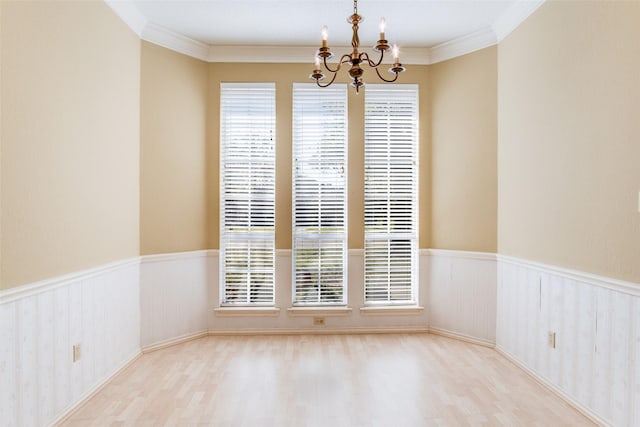 empty room featuring an inviting chandelier, crown molding, and light hardwood / wood-style flooring