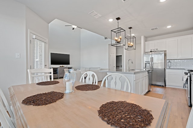 dining room with light hardwood / wood-style floors, an inviting chandelier, and sink