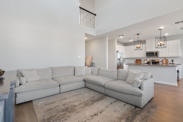 living room with light hardwood / wood-style flooring, a towering ceiling, and sink