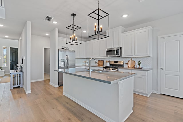 kitchen featuring backsplash, sink, light hardwood / wood-style flooring, white cabinetry, and stainless steel appliances