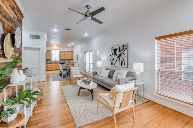 living room with light hardwood / wood-style flooring, ceiling fan, and ornamental molding