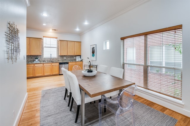 dining area with sink, crown molding, and light hardwood / wood-style flooring