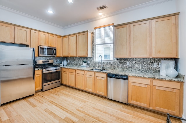 kitchen featuring sink, stainless steel appliances, light stone counters, light wood-type flooring, and ornamental molding