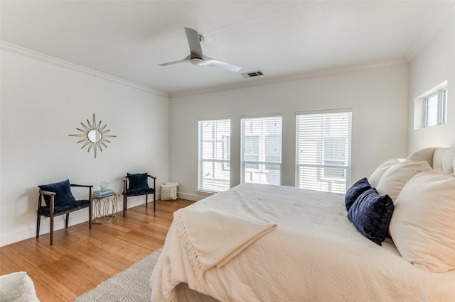 bedroom featuring hardwood / wood-style floors, multiple windows, crown molding, and ceiling fan