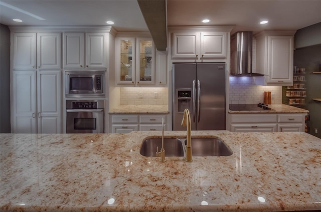 kitchen with white cabinetry, light stone counters, wall chimney range hood, and stainless steel appliances